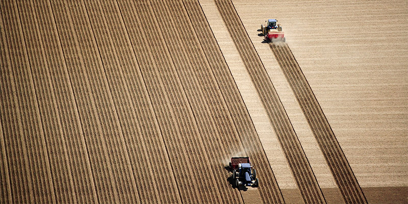 Two vehicles ploughing a field